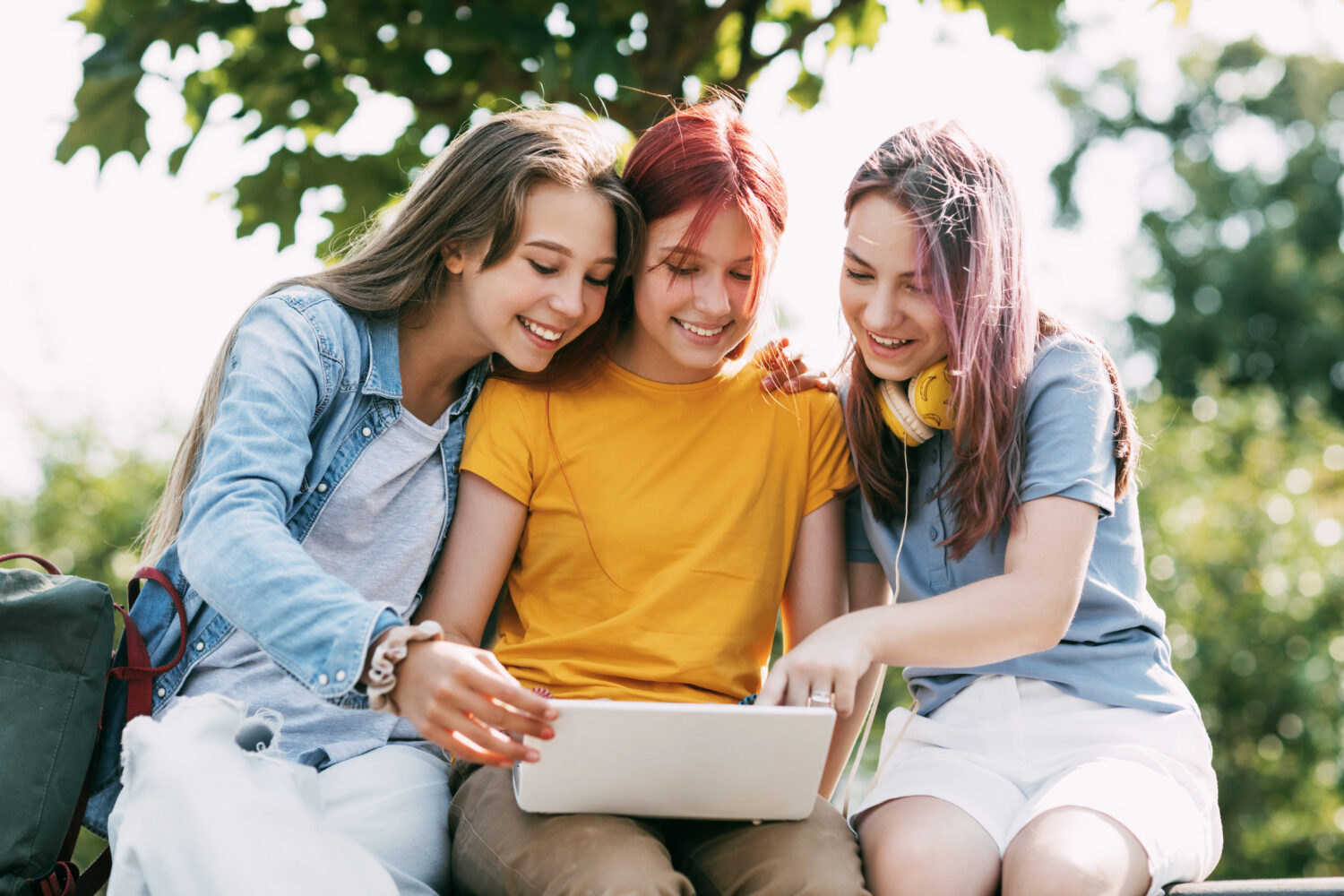 Drei Teenager-Mädchen kommunizieren via Tablet mit Freunden